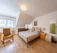 Priestranný 5-izbový rodinný dom (190 m²) s krásne upraveným 13a pozem - Spálňa v rodinnom dome s podlahou s dreveným dekorom, posteľou a kreslom.