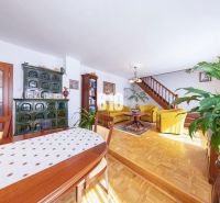 Priestranný 5-izbový rodinný dom (190 m²) s krásne upraveným 13a pozem - Obývacia izba v rodinnom dome s podlahou s dreveným dekorom, pecou a dreveným schodiskom.