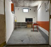 PREDAJ - Garáž na s pozemkom na Pionierskej ulici  - Priestor garáže s betónovou podlahou a pracovným stolom vo vnútri.