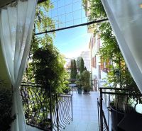 Prenájom prestížnej kancelárie 38 m2 v centre Piešťan - Kancelárie s balkónom obklopeným rastlinami, vchod cez biele závesy a kované zábradlie.