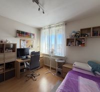 Ex. Moderný 4 iz byt po komplet. rekonštrukcii s lodžiou v Piešťanoch - Izba v 4-izbovom byte s podlahou s dreveným dekorom obsahuje posteľ, stôl a regály.