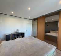 Ex. Moderný 3 iz. byt 90 m2 s garážou a záhradou v Dolnom Trhovišti - Spálňa s veľkou posteľou, zrkadlovou skriňou, podlahou s dreveným dekorom v 3-izbovom byte.