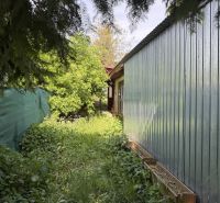 Ex. Moderný 3 iz. byt 90 m2 s garážou a záhradou v Dolnom Trhovišti - Záhrada pri dome v Dolnom Trhovišti s bohatou vegetáciou, plotom a plechovou stenou.