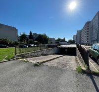 PREDAJ - Garáž na Mierovej ulici - Garáže na Mierovej ulici v Bratislave - Ružinove, obklopené panelákmi, pod modrou oblohou.