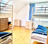 Rekreačný RD pri Oravskej Priehrade na Slanickej Osade - Izba so štyrmi posteľami, bielym nábytkom a modrými závesmi, vhodná pre rodinný dom.