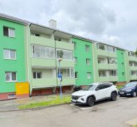 Na predaj 1-izbový byt Bratislavská ul., Dubnica Nad Váhom - Svetlozelený bytový dom na Bratislavskej ulici v Dubnici nad Váhom, zaparkované autá vpredu.