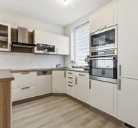 Zariadený 3 izb.byt, 229 m2 záhrada, 2 parkovacie miesta  - Svetlá kuchyňa s bielymi skrinkami a podlahou s dreveným dekorom v 3-izbovom byte.