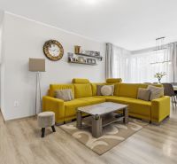 Zariadený 3 izb.byt, 229 m2 záhrada, 2 parkovacie miesta  - Obývacia izba v 3-izbovom byte s podlahou s dreveným dekorom a žltou sedačkou.