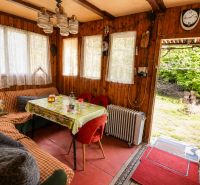 Znížená cena_Slnečný pozemok s chatou-Modra Harmónia - Interiér chaty s dreveným obložením, pohodlným sedením a výhľadom do záhrady.