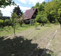 Znížená cena_Slnečný pozemok s chatou-Modra Harmónia - Chata na ulici Harmónia v Modre obklopená záhradou a zelenými stromami.
