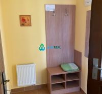 Apartmánový dom na predaj blízko termálneho kúpaliska - Interiér hotelovej izby s vešiakovou stenou, skrinkou a radiátorom.