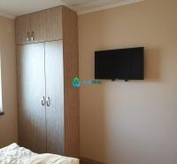 Apartmánový dom na predaj blízko termálneho kúpaliska - Šatníková skriňa, televízor na stene a posteľ v hoteli a penzióne.
