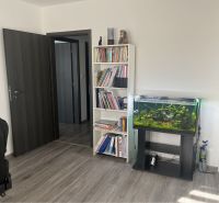 HORNÁ POTOŇ – 4-IZBOVÝ RODINNÝ DOM - NOVOSTAVBA - Knižnica, akvárium a kreslo v izbe rodinného domu s podlahou s dreveným dekorom.