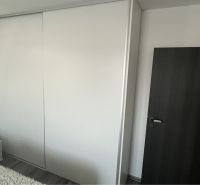 HORNÁ POTOŇ – 4-IZBOVÝ RODINNÝ DOM - NOVOSTAVBA - Biela vstavaná skriňa so zásuvkami, tmavé dvere, podlaha s dreveným dekorom v rodinnom dome.