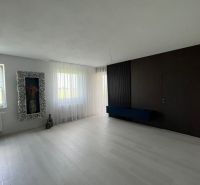 Luxusný byt na prenájom úplne nový kompletne zariadený s garážou. - Interiér priestrannej miestnosti s bielou podlahou a tmavými stenami v 3-izbovom byte.