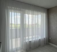 Luxusný byt na prenájom úplne nový kompletne zariadený s garážou. - Biela záclona v 3-izbovom byte, podlaha s dreveným dekorom a svetlá stena.