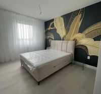 Luxusný byt na prenájom úplne nový kompletne zariadený s garážou. - Spálňa v 3-izbovom byte s dekoratívnou tapetou a podlahou s dreveným dekorom.