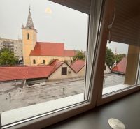 Voľný od 1 oktobra.Byt v centre mesta na prenájom - Výhľad z okna 1-izbového bytu na kostol v Dunajskej Strede počas zamračeného dňa.