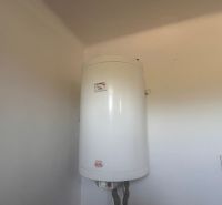 Rodinný dom okamžite obývateľný. - Biely elektrický bojler inštalovaný na stene v rodinnom dome.