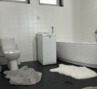 Ůžasný rodinný dom v obci Trstice. - Kúpeľňa v rodinnom dome s vaňou, práčkou, toaletou a chlpatými koberčekmi.