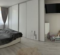 Ůžasný rodinný dom v obci Trstice. - Spálňa v rodinnom dome s podlahou s dreveným dekorom, záclony, zrkadlo a televízia.