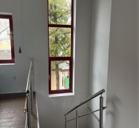 Prenájom nebytového priestoru na podnikateľské účely v CENTRE Dunajske - Schodisko v budove s oknami s červeným rámom a podlahou s dreveným dekorom.