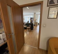 Znížená cena!!☎️ - Interiér s podlahou s dreveným dekorom a otvorenými dverami vedúci do kancelárie.