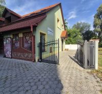 Na prenájom polyfunkčný objekt v DS - Budova v Dunajskej Strede s bránou, zelenou fasádou a reklamnými plochami.