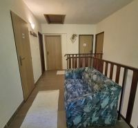Prenájom 2-izbového apartmánu v Dunajskej Strede - Chodba so sedačkou, tromi dverami a schodiskovým zábradlím v 2-izbovom byte.