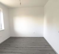 Výrazná zľava do konca októbra - 3izbový rodinný dom v obci Orechová P - Prázdna miestnosť s bielymi stenami a podlahou s dreveným dekorom v rodinnom dome.
