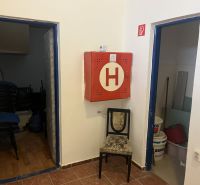 Exkluzívny obchodný priestor na prenájom v centre Dunajskej Stredy – u - Interiér obchodných priestorov s hasičskou skriňou, stoličkou a skladovacími miestnosťami.
