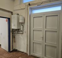Exkluzívny obchodný priestor na prenájom v centre Dunajskej Stredy – u - Biely kotol na stene obchodných priestorov s podlahou s dreveným dekorom.