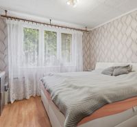 Exkluzívne-4 izbový byt na PREDAJ v Dunajskej Strede - Spálňa v 4-izbovom byte s podlahou s dreveným dekorom a oknom s bielym závesom.