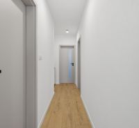 Exkluzívne na predaj – moderný 3-izbový byt so záhradou v Hornej Potôn - Chodba s bielymi stenami a podlahou s dreveným dekorom v 3-izbovom byte.