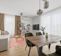 Exkluzívne na predaj – moderný 3-izbový byt so záhradou v Hornej Potôn - Obývačka v 3-izbovom byte s jedálenským stolom a podlahou s dreveným dekorom.