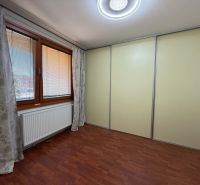 Predaj 3-izbového bytu, Dunajská Streda - Izba v 3-izbovom byte s veľkým oknom a skriňou, podlaha s dreveným dekorom.
