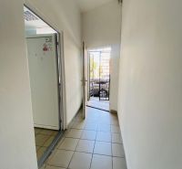 -Na prenájom obchodný priestor 30 m2 v centre mesta Dunajská Streda - Úzky chodba s dlažbou, vedúca k otvoreným dverám v obchodných priestoroch.