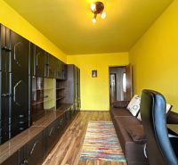 Na predaj kompletne zariadený 3 izbový byt s klimatizáciou aj s balkón - Žlté steny obývačky v 3-izbovom byte s tmavým nábytkom a dreveným dekorom.