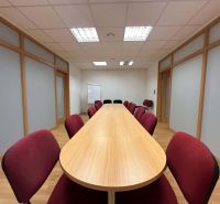 Na prenájom menšia  kancelária v centre mesta DS - 12,94 m2 - Konferenčná miestnosť v kanceláriách s dlhou drevenou stolom a podlahou s dreveným dekorom.