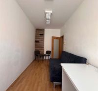 Na prenájom menšia  kancelária v centre mesta DS - 12,94 m2 - Interiér kancelárie s pohovkou, stolom a podlahou s dreveným dekorom.