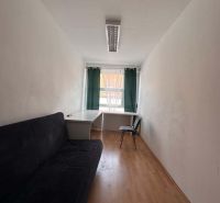 Na prenájom menšia  kancelária v centre mesta DS - 12,94 m2 - Úzka kancelária s pohovkou, stolom a stoličkou; podlaha s dreveným dekorom.