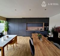 Znížená cena    Luxusný 4-izbový rodinný dom s letnou kuchyňou a nádhe - Kuchyňa v rodinnom dome s podlahou s dreveným dekorom a veľkým stolom.