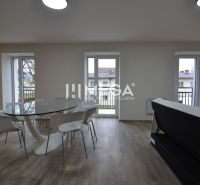 PREDAJ MODERNE ZREKONŠTRUOVANÝCH BYTOV V STRÁŽSKOM (BYT H) - Jedálenský priestor v 3-izbovom byte s podlahou s dreveným dekorom a skleneným stolom.