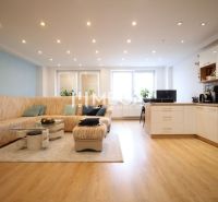 ZNÍŽENÁ CENA EXKLUZÍVNE NA PREDAJ: 3-IZBOVÝ BYT 94 m² | PARKOVACIE MIE - Obývacia izba s kuchyňou, svetlý interiér, sedačka, podlaha s dreveným dekorom, 3-izbový byt.