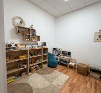 Na prenájom kancelársky priestor 30 m² – Trnava Františkánska - Detský kútik v kancelárii s regálmi plnými hračiek, podlaha s dreveným dekorom.