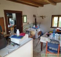 Veľký, vyše 4,5Ha slnečný pozemok s chalupou v strede, na lazoch, pri  - Interiér chaty s kuchynským stolom, podlahou s dreveným dekorom a kachľovou pecou.