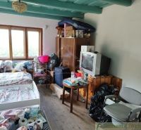 Veľký, vyše 4,5Ha slnečný pozemok s chalupou v strede, na lazoch, pri  - Miestnosť v chate s posteľou, televízorom a rozličným uloženým neporiadkom.
