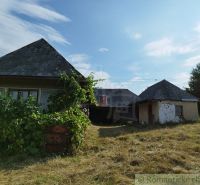 Veľký, vyše 4,5Ha slnečný pozemok s chalupou v strede, na lazoch, pri  - Chaty v Hrušove na pozemku zarastenom trávou, obklopené zeleňou pod modrou oblohou.