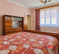 Rodinný dom s veľkým pozemkom 2 908 m² v obci Žiar - Spálňa v rodinnom dome s dreveným nábytkom a kvetinovým prehozem na posteli.