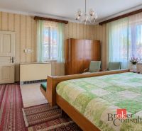 Rodinný dom s veľkým pozemkom 2 908 m² v obci Žiar - Spálňa v rodinnom dome s vintage nábytkom, tapetami a zelenými závesmi.